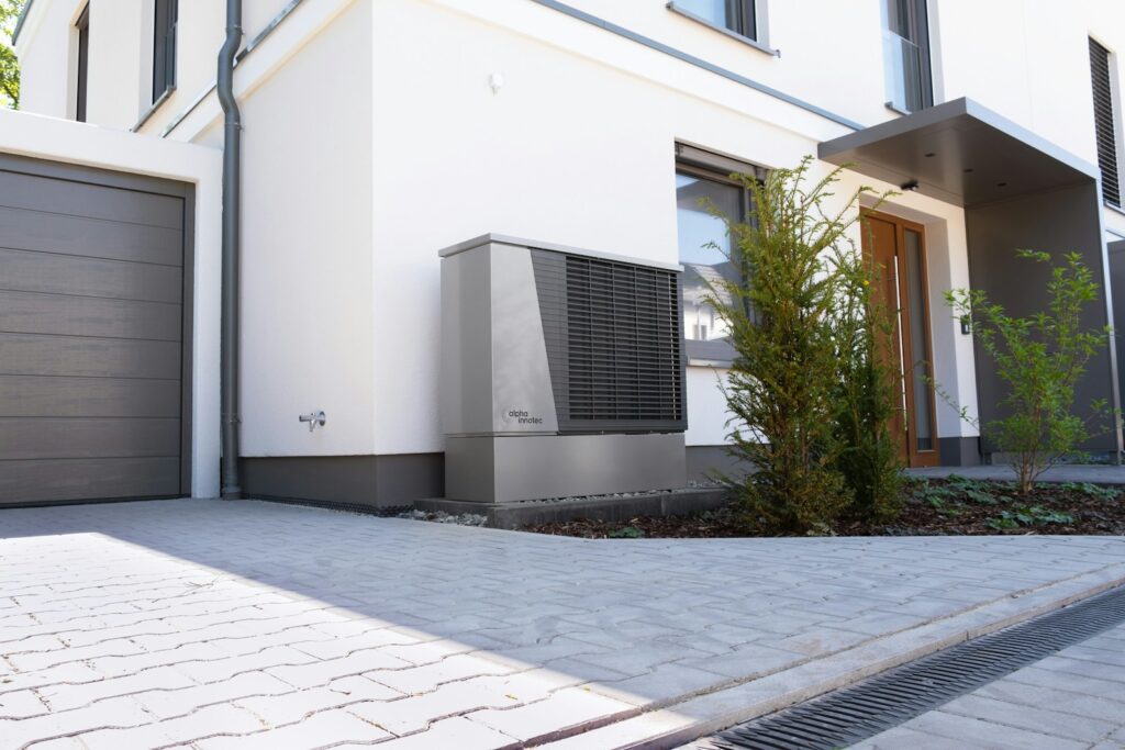 Das Außengerät einer Wärmepumpe steht vor einem Einfamilienhaus